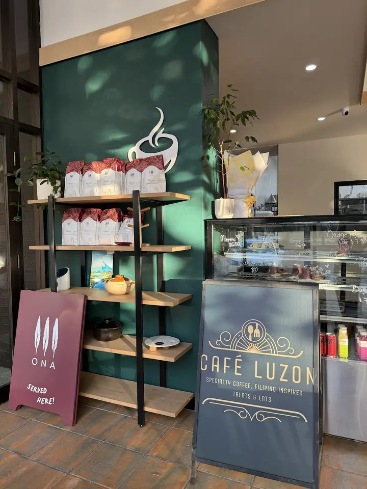 Inside Café Luzon: green wall, shelves of ONA coffee and the Café Luzon sign